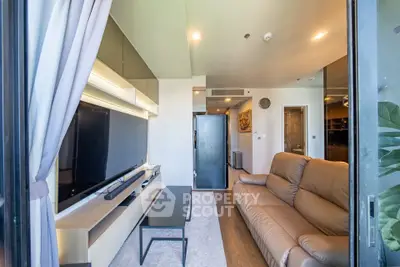 Modern living room with sleek design and large TV, featuring a cozy brown leather sofa and stylish decor.