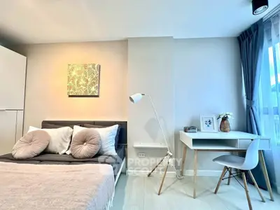 Modern bedroom with stylish decor and natural light, featuring a cozy bed and a sleek study desk.