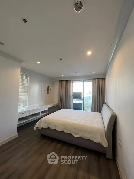 Spacious bedroom with modern decor and large window offering natural light.