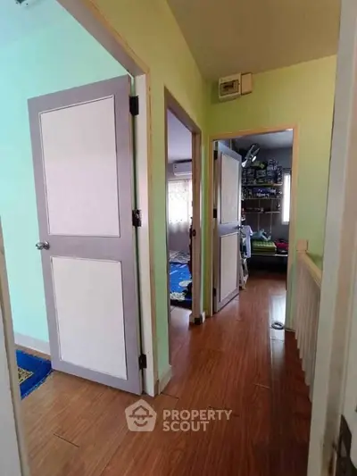 Bright hallway with wooden flooring and open doors leading to rooms