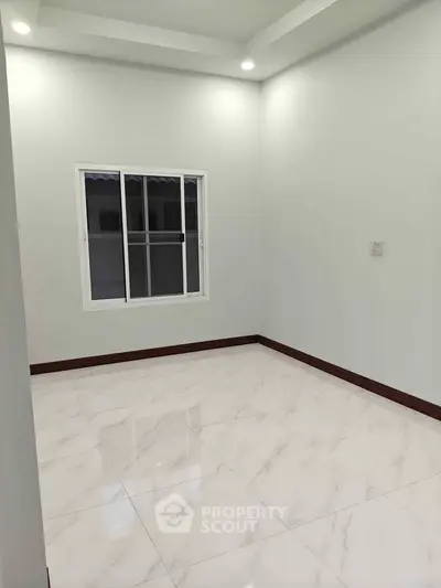 Spacious empty room with glossy white tile flooring and a large window.