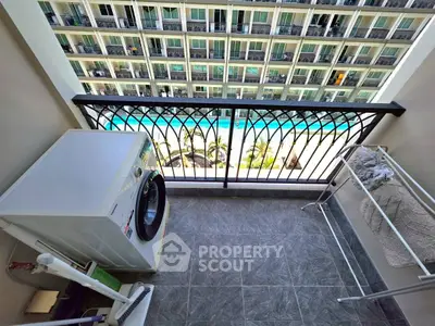 Charming balcony with pool view, featuring a washing machine and drying rack, perfect for urban living.