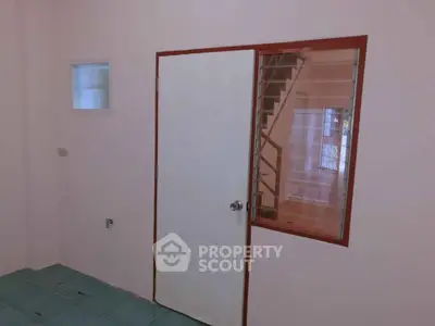 Minimalist interior with white door and staircase view, ideal for compact living spaces.