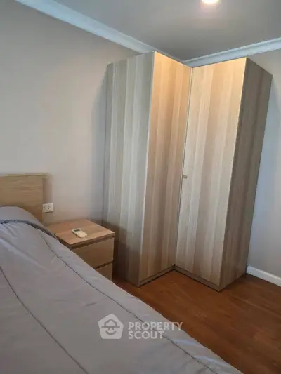 Cozy bedroom with wooden wardrobe and bedside table, perfect for modern living.