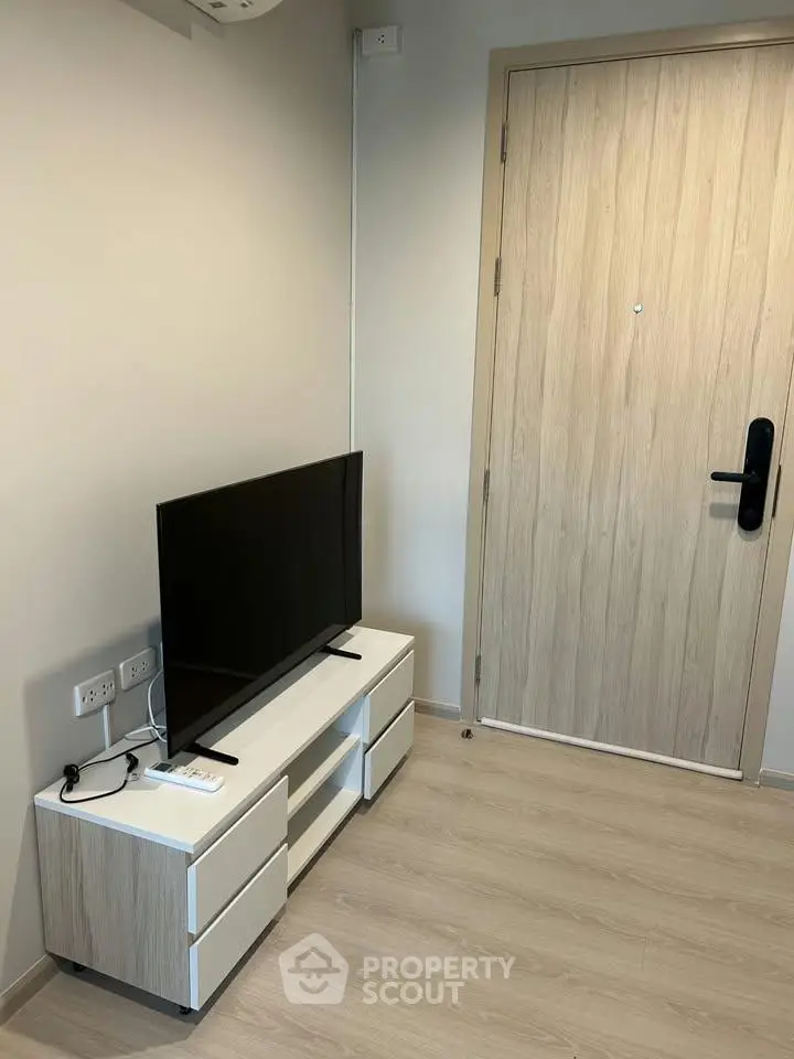 Modern apartment entrance with sleek TV stand and flat-screen TV, showcasing minimalist interior design.