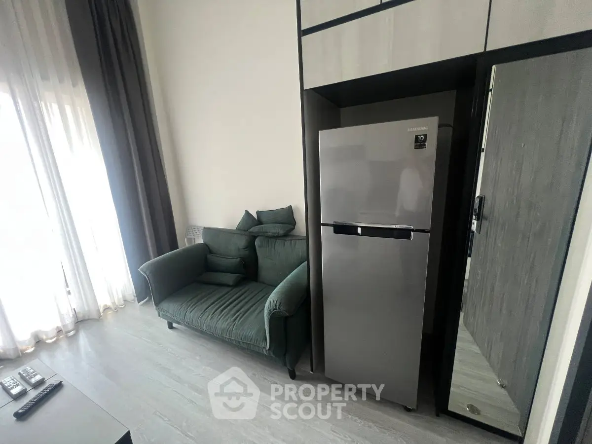 Modern living room with sleek fridge and cozy green sofa, perfect for urban living.