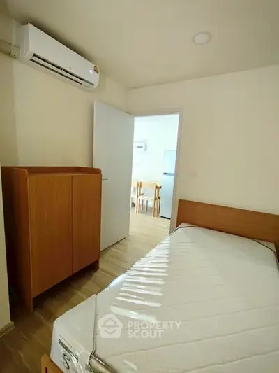 Cozy bedroom with wooden furniture and air conditioning, perfect for a comfortable living experience.