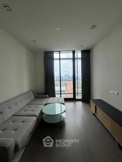 Modern living room with large window and city view, featuring sleek furniture and minimalist design.