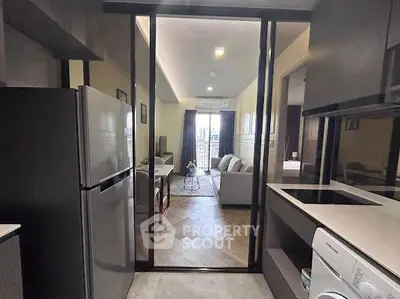 Modern apartment interior with open kitchen and cozy living room, featuring sleek appliances and stylish decor.