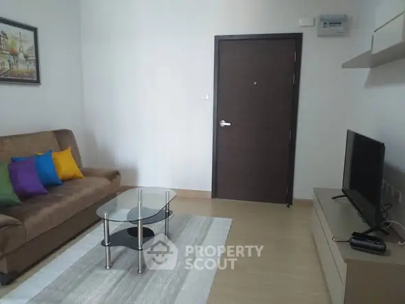 Modern living room with cozy sofa, glass coffee table, and flat-screen TV, perfect for relaxation.