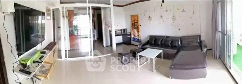 Spacious modern living room with sleek furniture and large windows offering natural light.