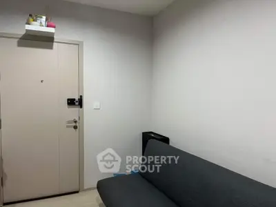 Minimalist apartment entrance with gray sofa and neutral walls