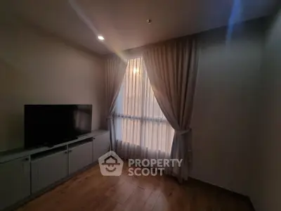 Cozy living room with elegant curtains and modern TV setup, perfect for relaxation.