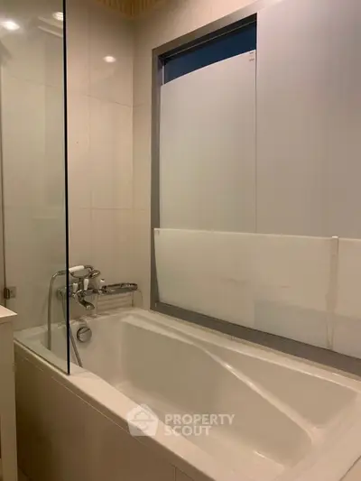 Modern bathroom with sleek bathtub and frosted glass window