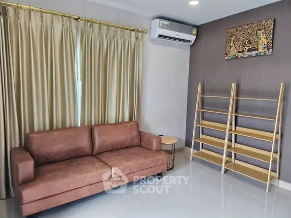 Modern living room with brown leather sofa and wooden shelves, featuring elegant curtains and air conditioning.