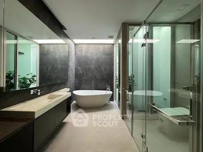 Luxurious modern bathroom with freestanding tub and glass shower enclosure.