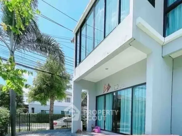 Modern two-story house with large windows and lush greenery, perfect for family living.