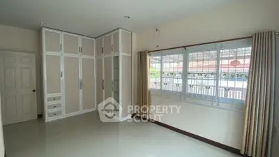Spacious bedroom with large window and built-in wardrobe, offering ample natural light and storage.