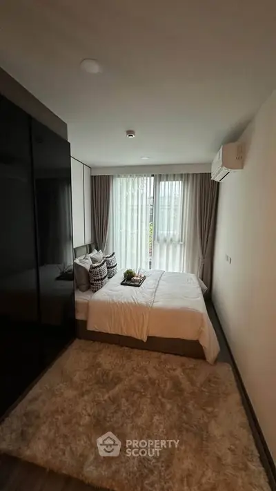 Cozy modern bedroom with plush carpet and large window for natural light.
