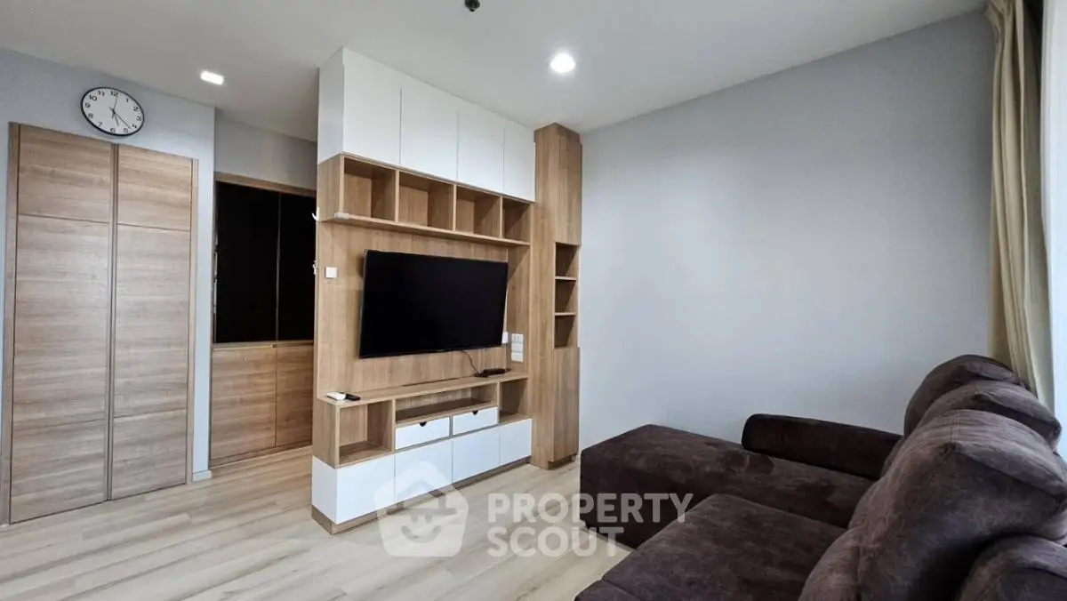 Modern living room with sleek wooden cabinetry and large TV