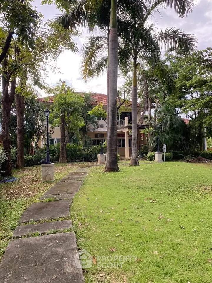 Charming villa with lush garden and tall palm trees, perfect for serene living.