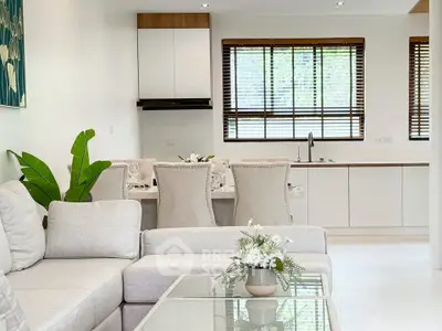Elegant open-layout living room with modern kitchen, featuring neutral tones and stylish decor.