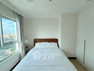 Bright bedroom with city view, featuring a cozy bed and built-in wardrobe, perfect for urban living.