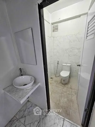 Compact bathroom with modern fixtures and marble tiles, ideal for efficient space utilization.