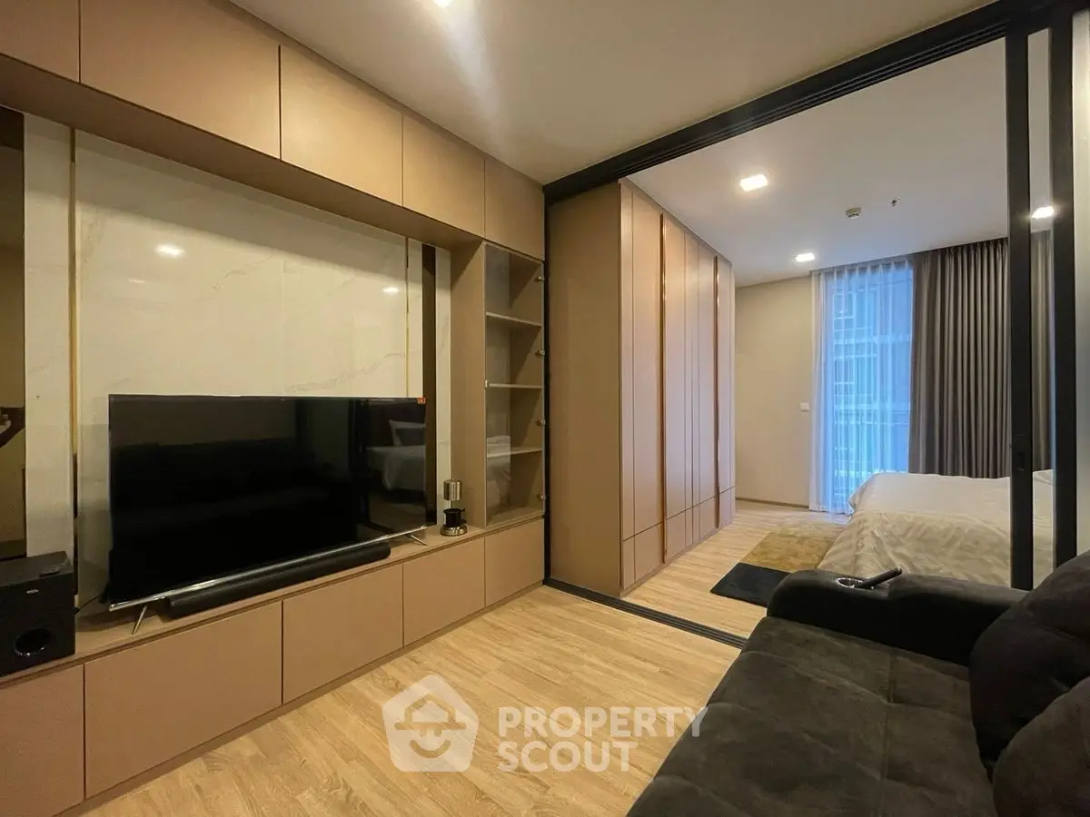 Modern living room with sleek TV setup and cozy bedroom view