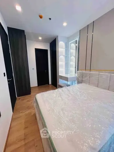 Modern bedroom with sleek design and ample natural light, featuring a stylish bed and wooden flooring.