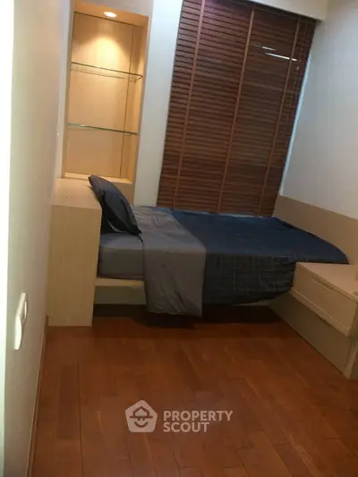 Cozy bedroom with wooden flooring and built-in shelves, perfect for a compact living space.