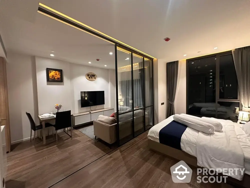 Modern studio apartment with glass partition, cozy living area, and elegant bedroom setup.