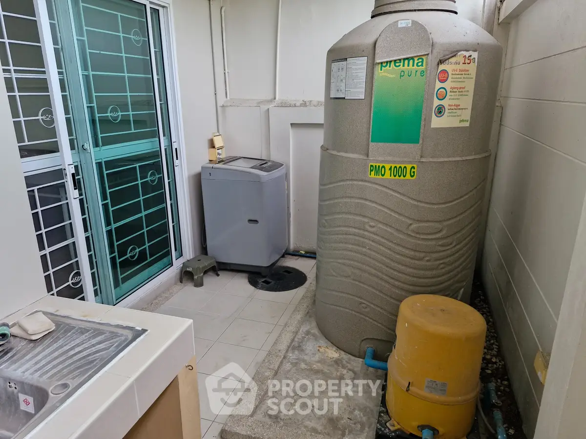 Outdoor utility area with water tank and washing machine in modern home