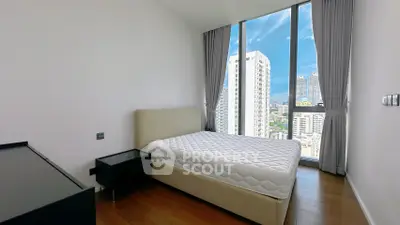 Modern bedroom with large windows offering stunning city views in a high-rise apartment.