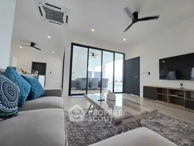 Spacious modern living room with stylish decor and large glass doors opening to balcony.