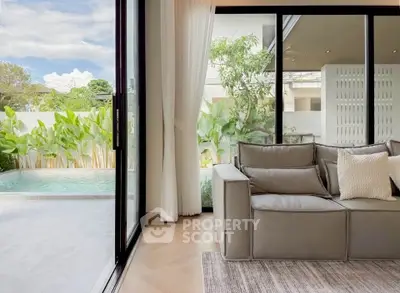 Luxurious living room with pool view and modern decor, featuring large sliding glass doors and elegant furnishings.