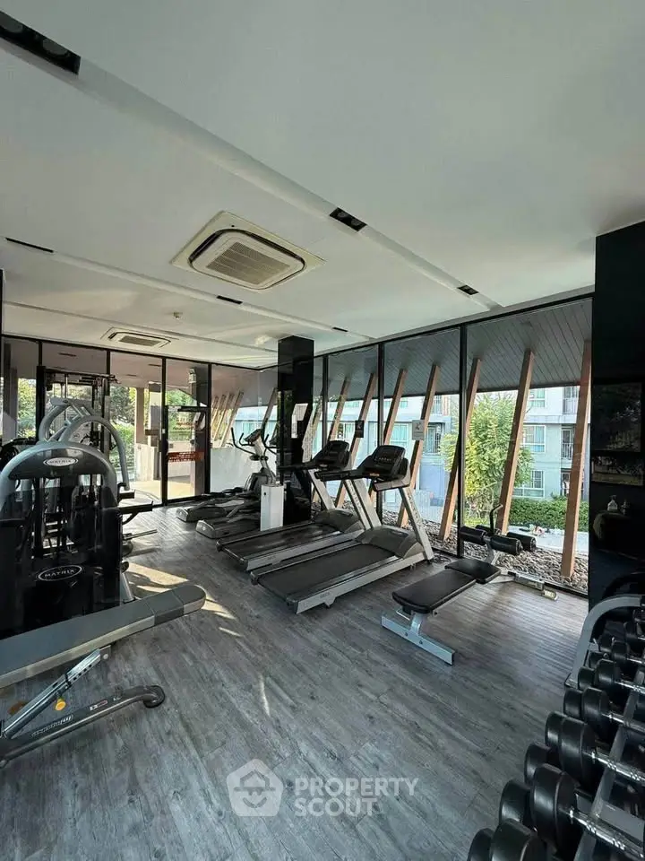 Modern gym with state-of-the-art equipment and large windows offering a scenic view.