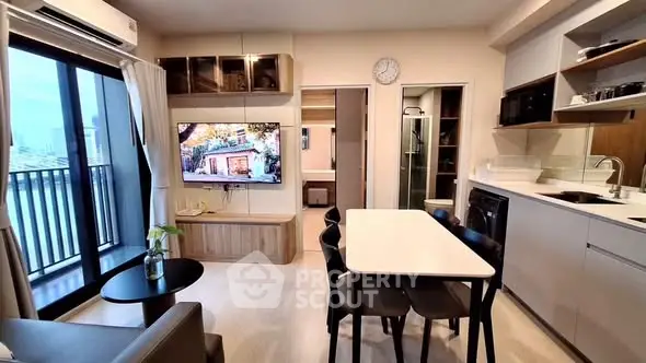 Modern living room with open kitchen, featuring sleek furniture and a balcony view.