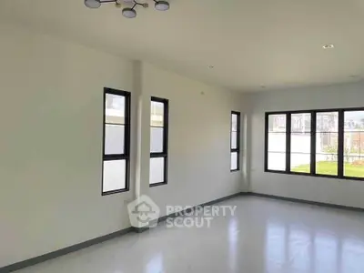 Spacious empty room with large windows and modern lighting, perfect for customization.
