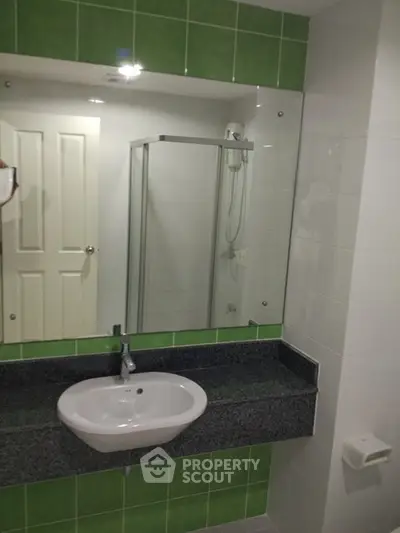 Modern bathroom with green tiles and glass shower enclosure