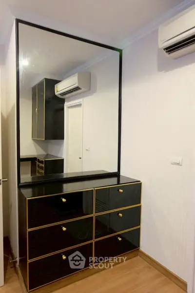 Stylish bedroom with modern dresser and large mirror, featuring sleek air conditioning unit.