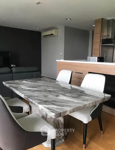 Modern dining area with marble table and stylish chairs in open-plan living space.