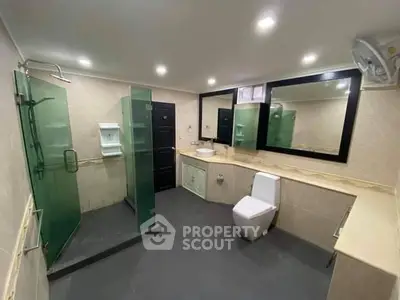 Spacious modern bathroom with large mirror, glass shower enclosure, and sleek fixtures, perfect for a contemporary home.