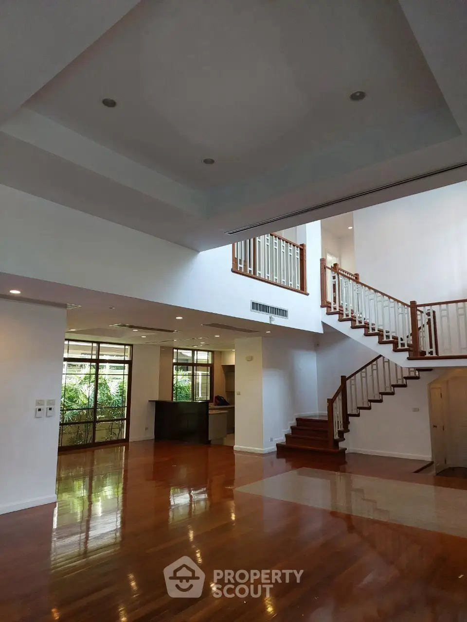 Spacious living room with high ceilings and elegant wooden staircase