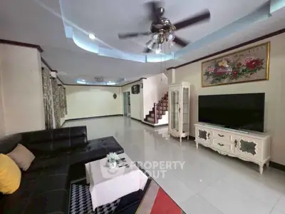 Spacious living room with modern decor and ceiling fan, ideal for family gatherings.