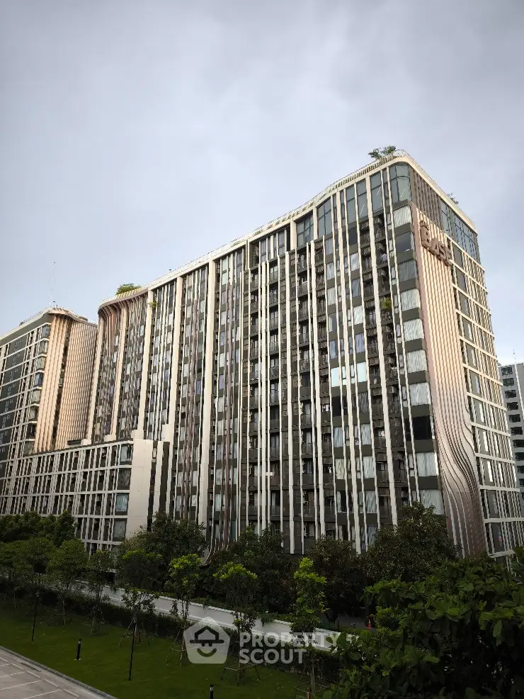 Modern high-rise residential building with lush greenery and sleek architectural design.