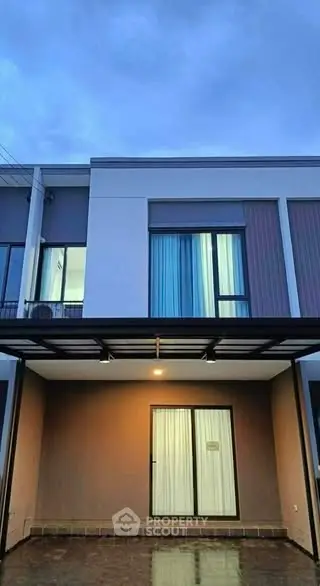 Modern two-story house exterior with large windows and covered entrance.