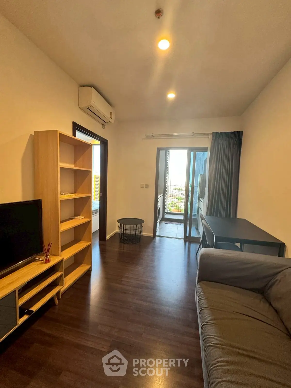 Modern living room with balcony view, featuring sleek furniture and ample natural light.