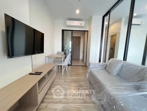 Modern living room with sleek furniture and wall-mounted TV in a stylish apartment.