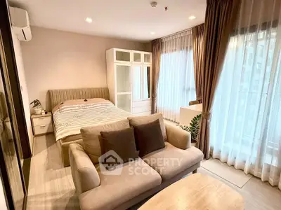 Spacious bedroom with cozy seating area and large windows in modern apartment.